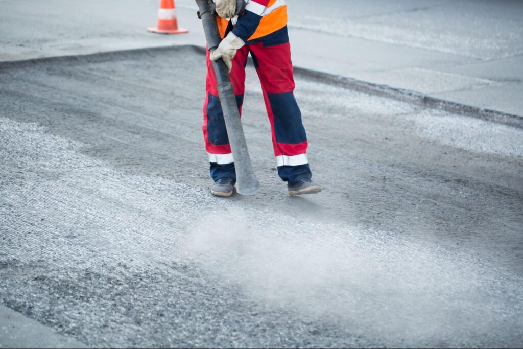 Road worker smoothing asphalt during road maintenance project.