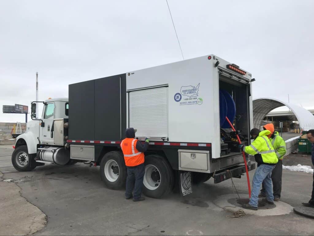 Urban maintenance crew using a truck for sewer cleaning operations.