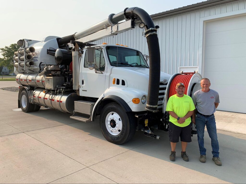 Two vacuum truck operators with equipment ready for hire.