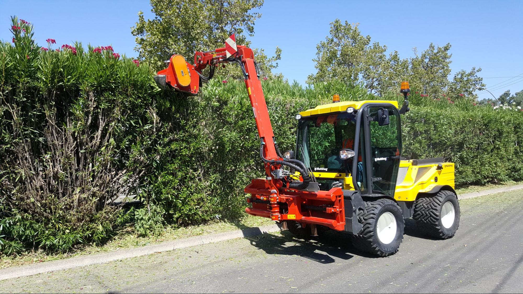 Efficient hedge maintenance with specialized trimming vehicle in landscaped area.