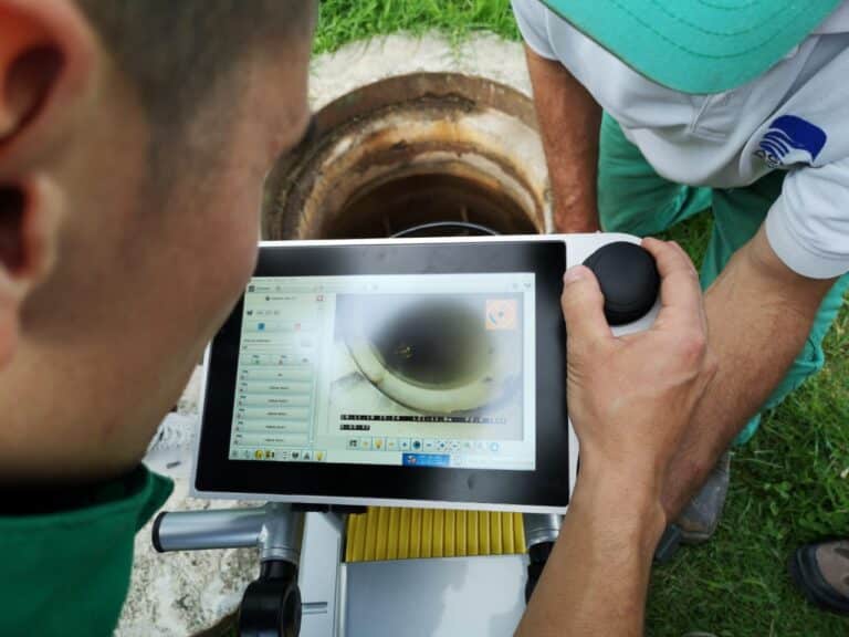 Technicians using tablet technology for advanced sewer pipe inspections.