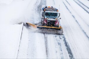 Snowplow removing snow for safer winter road conditions during a snowstorm.