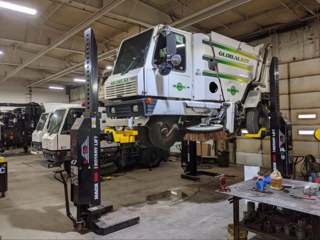 Street sweeper receiving repair in a maintenance workshop.
