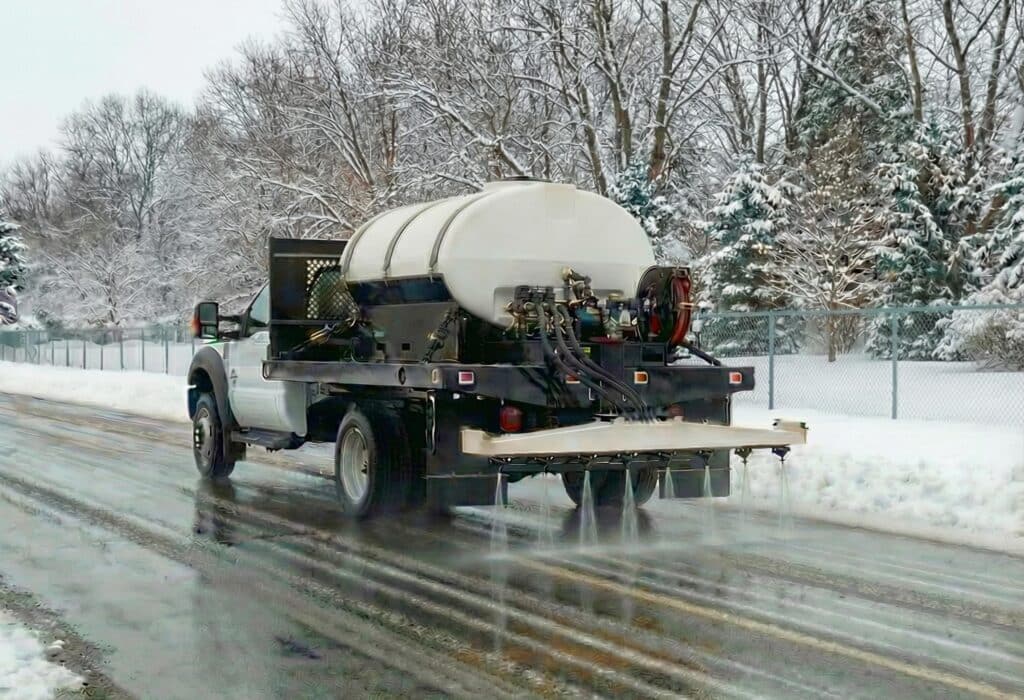Snow treatment vehicle clearing icy roads during winter weather conditions.