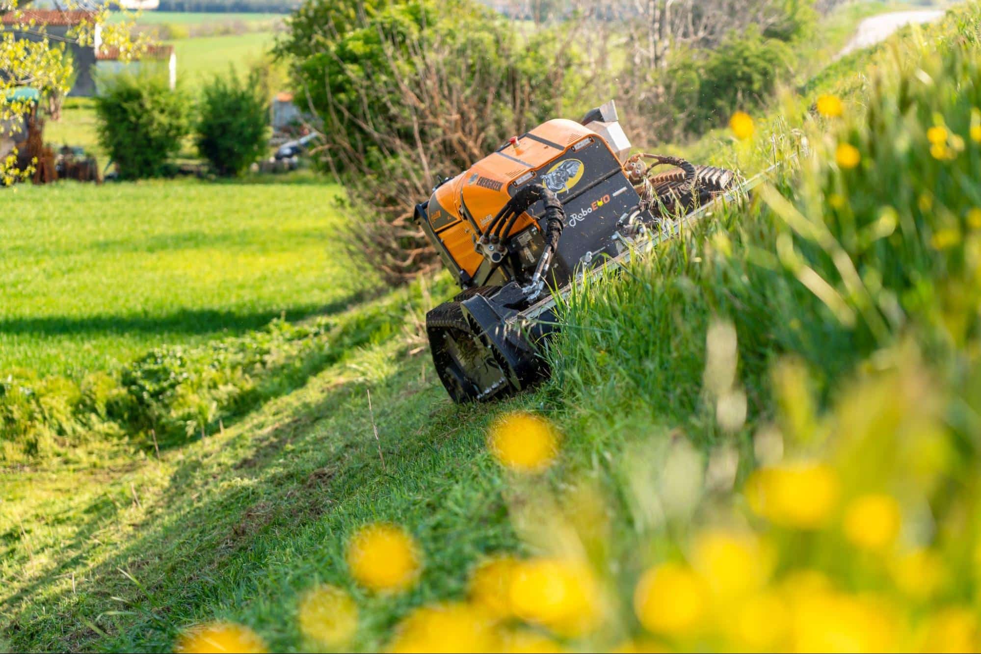 Remote-controlled mower efficiently trimming grass on a hillside.