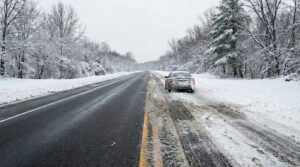 Snow-covered road winding through a quiet winter landscape.