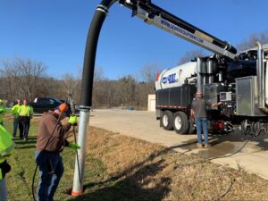 Workers using a vacuum truck for efficient wastewater management in a rural area.