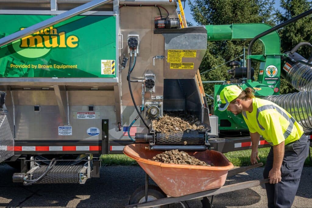 Worker operating a Mulch Mule for efficient garden landscaping and maintenance tasks.