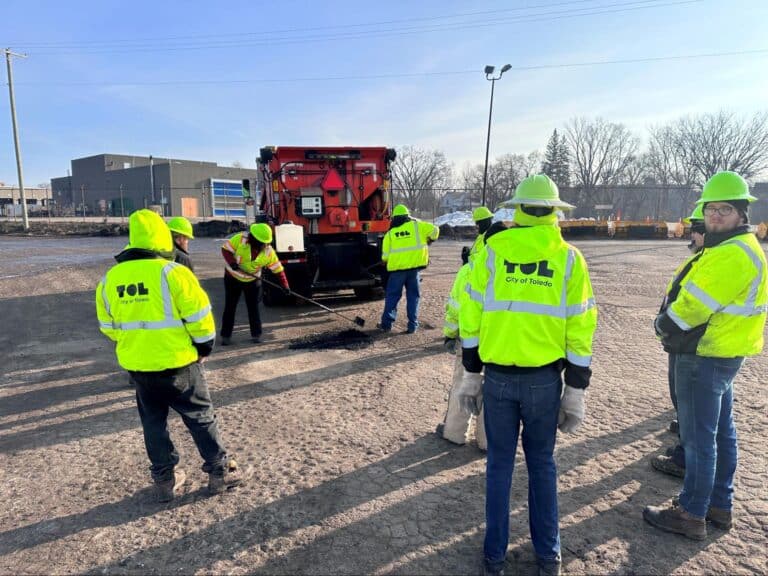 Road crew safety training with equipment in a parking lot.