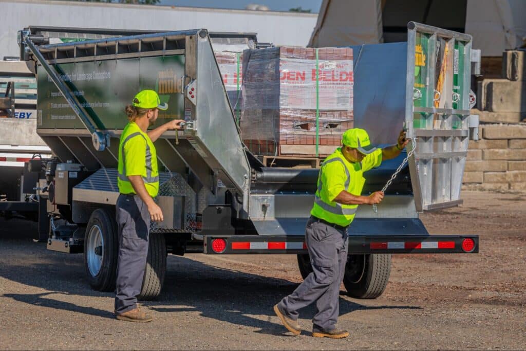 Workers unloading mulch materials from a truck at a construction site.