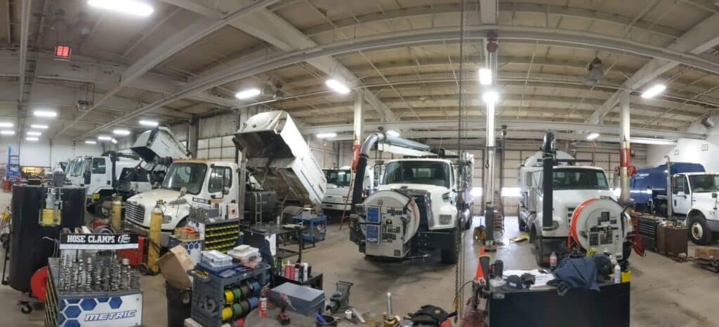 Heavy equipment being repaired in a busy workshop filled with tools and machinery.