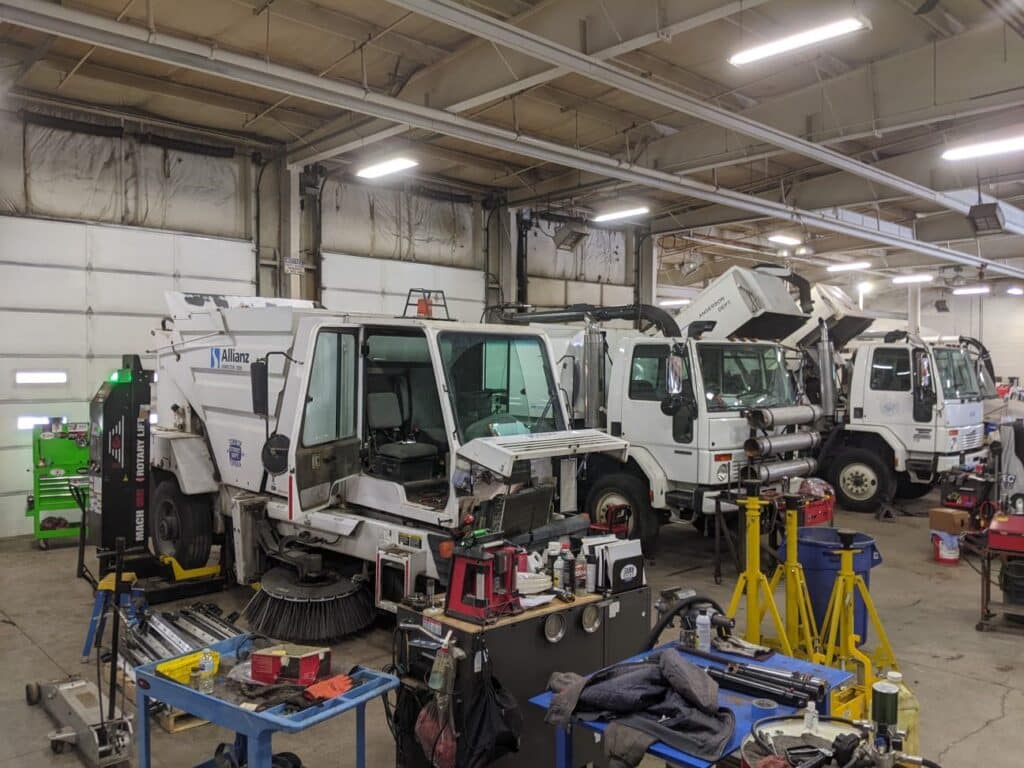 Heavy machinery repair in a bustling workshop with various tools and vehicles.