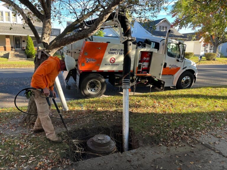 Utility worker operating a Hydro Spade for maintenance on a city street.