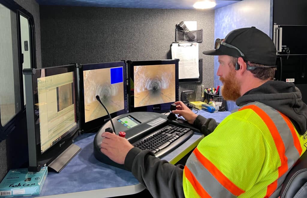 Technician operating IBAK equipment for advanced pipe inspection on multiple monitors.