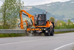 Road maintenance vehicle clearing vegetation along a scenic highway.