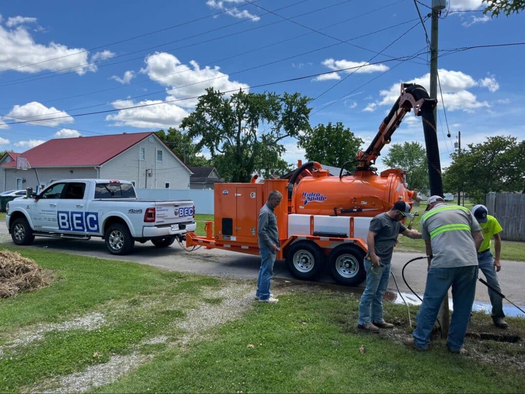 Utility crew operating hydrovac trailer to excavate safely on residential street.