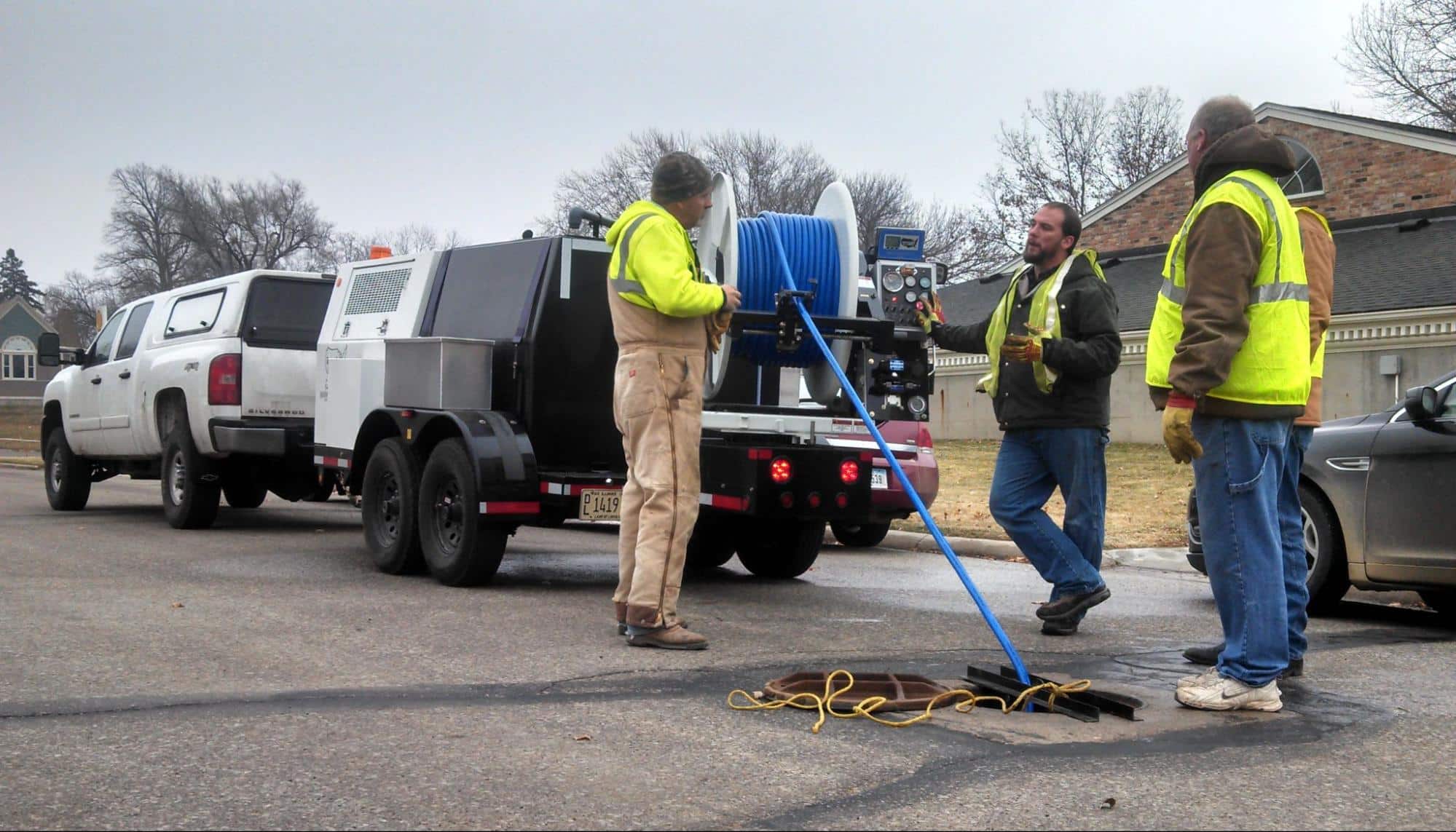Utility workers repairing a drainage system on a suburban street.