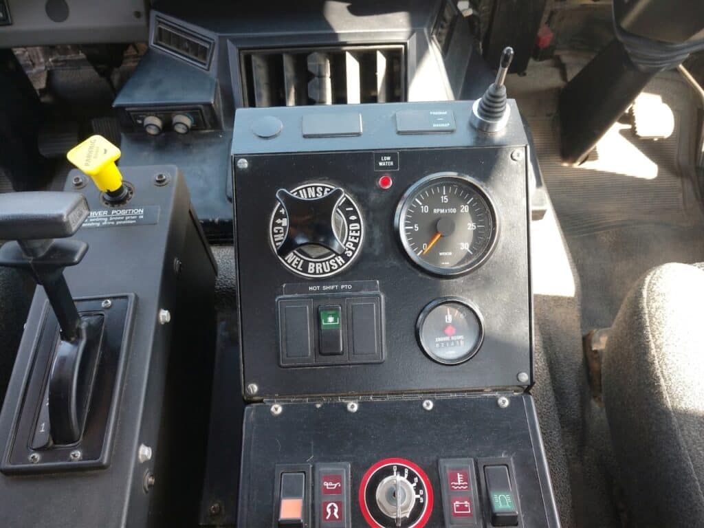 Street sweeper control panel featuring essential gauges and operation switches.