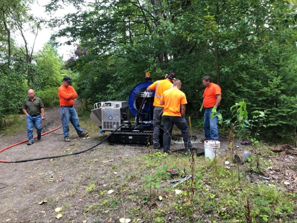 Crew using machinery for forest maintenance tasks in a wooded area.