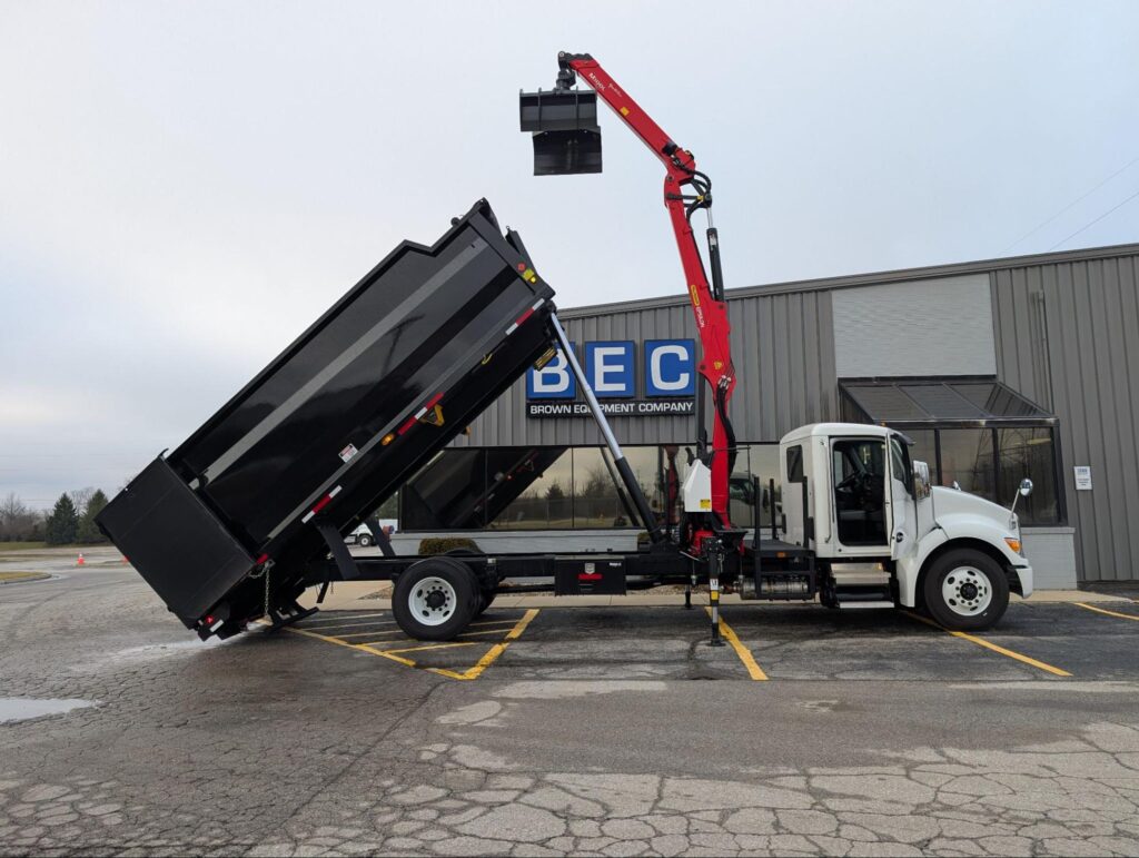 Heavy-duty grapple dump truck lifting materials at Brown Equipment Company.