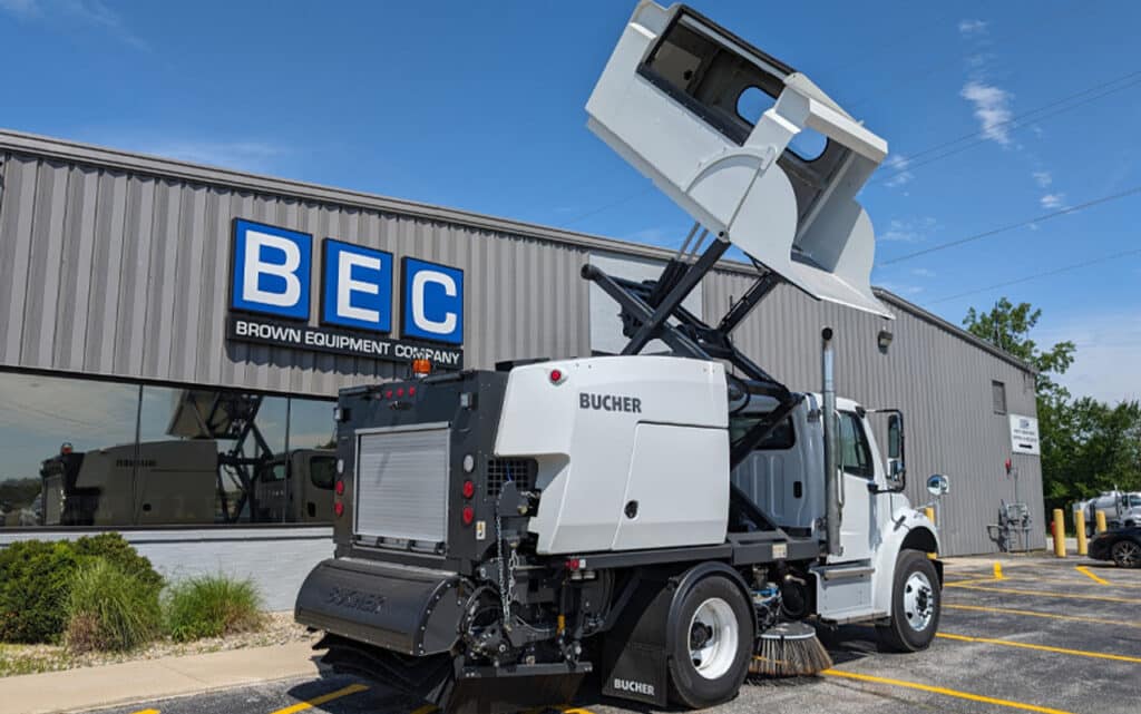Street sweeper operating outside Brown Equipment Company, showcasing advanced cleaning technology.