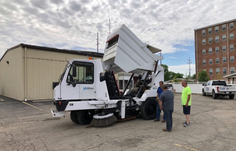 Crew inspects street sweeper for maintenance and operational efficiency in the city.