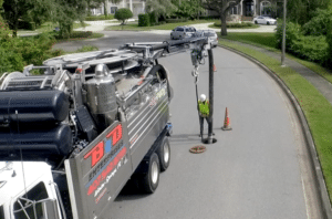 Water recycling truck servicing city sewer lines on a residential street.