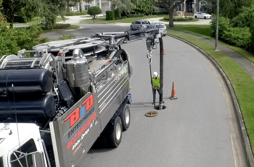 Water recycling truck servicing city sewer lines on a residential street.